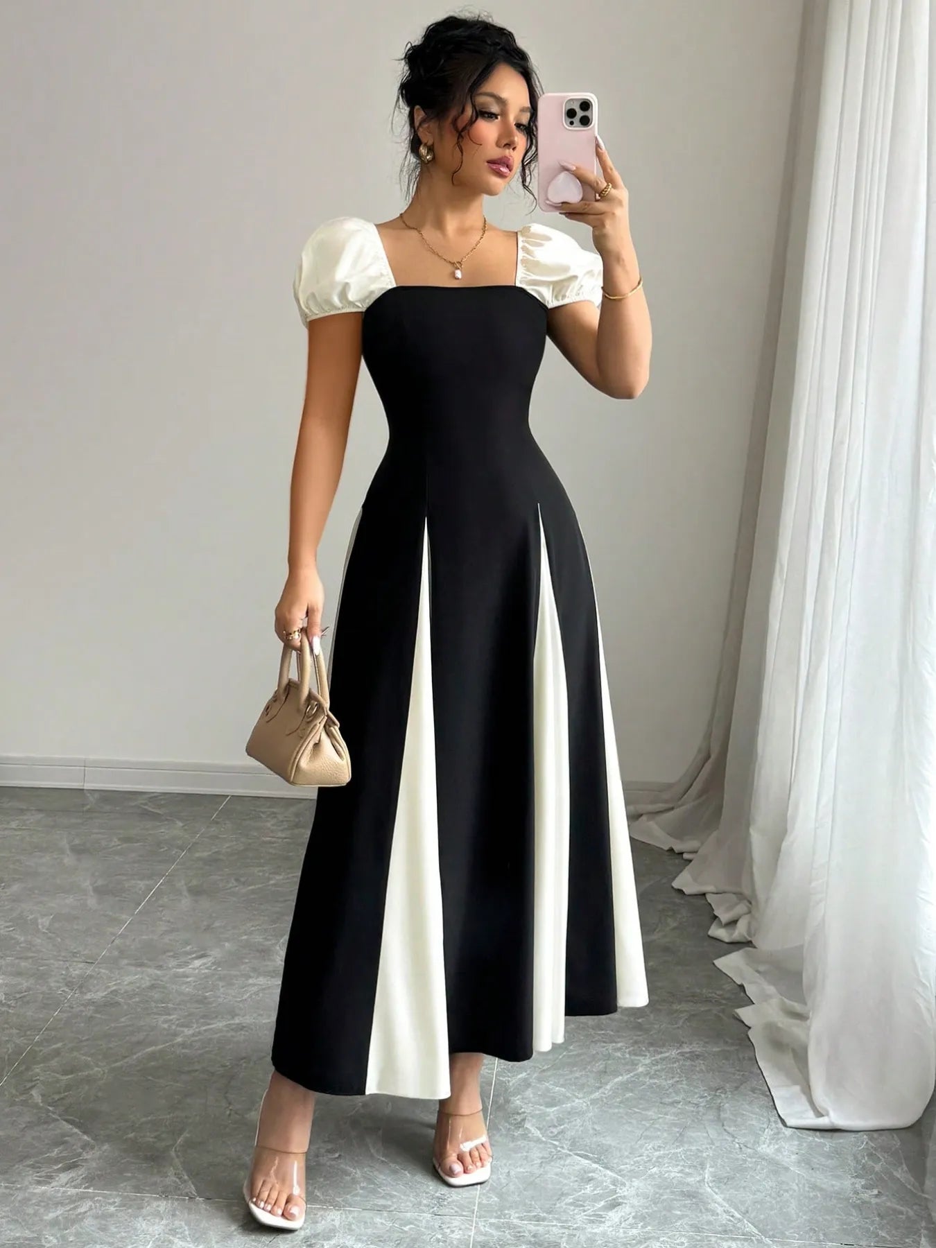 contrast puff sleeve midi dress in black with white side panels and square neckline model holding beige handbag