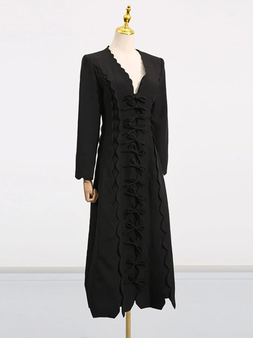 black long sleeve bow front midi dress on mannequin with scalloped V neckline and row of bows