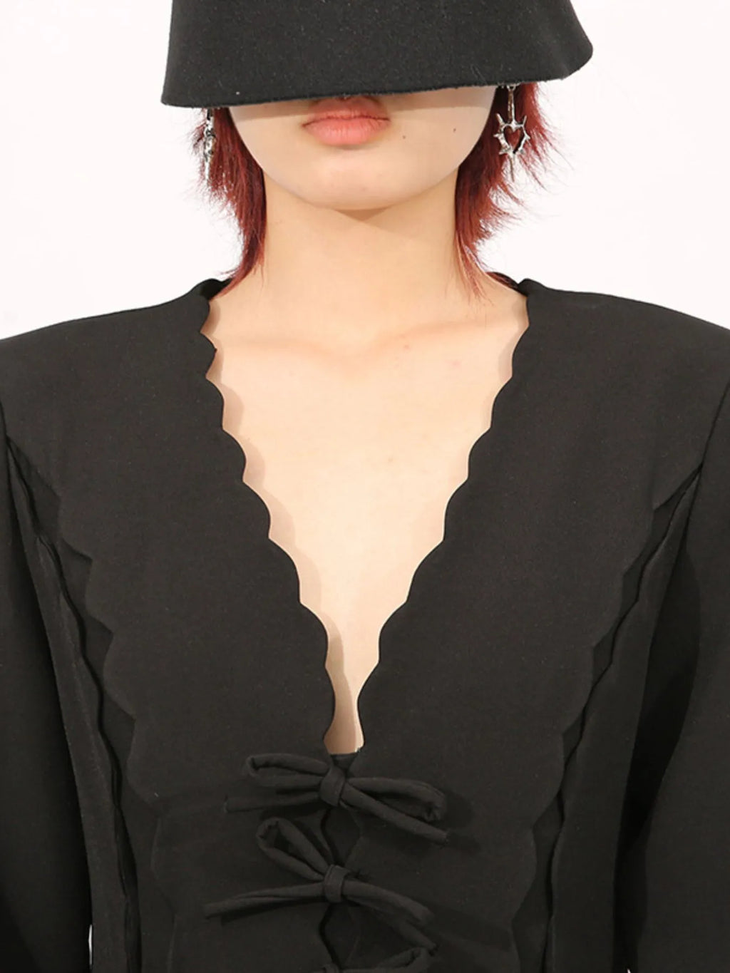 model wearing a long sleeve bow front midi dress in black with scalloped V neckline and star earrings