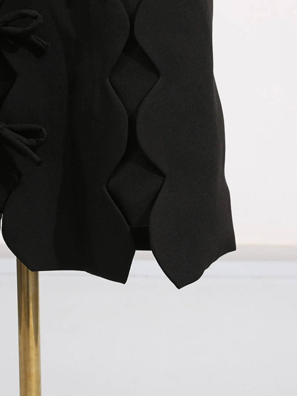 black long sleeve bow front midi dress close up showing scalloped hem and side bow details