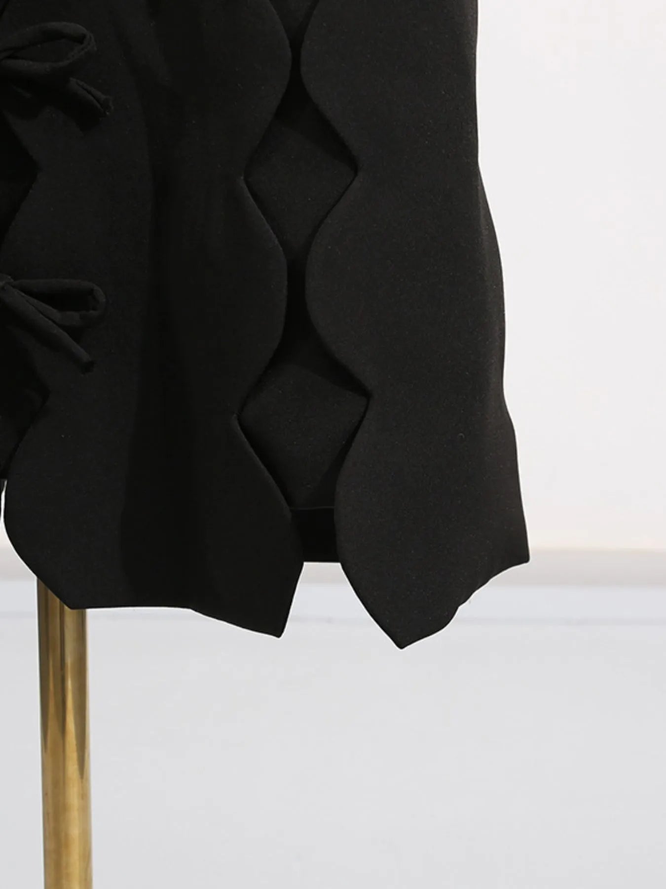black long sleeve bow front midi dress close up showing scalloped hem and side bow details