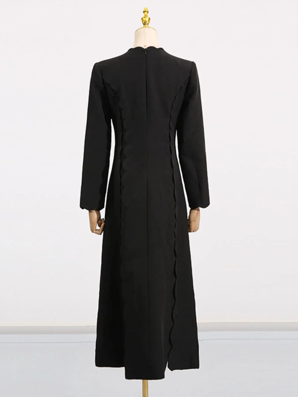 Back view of black long sleeve bow front midi dress on mannequin with fitted waist and side scallop detailing