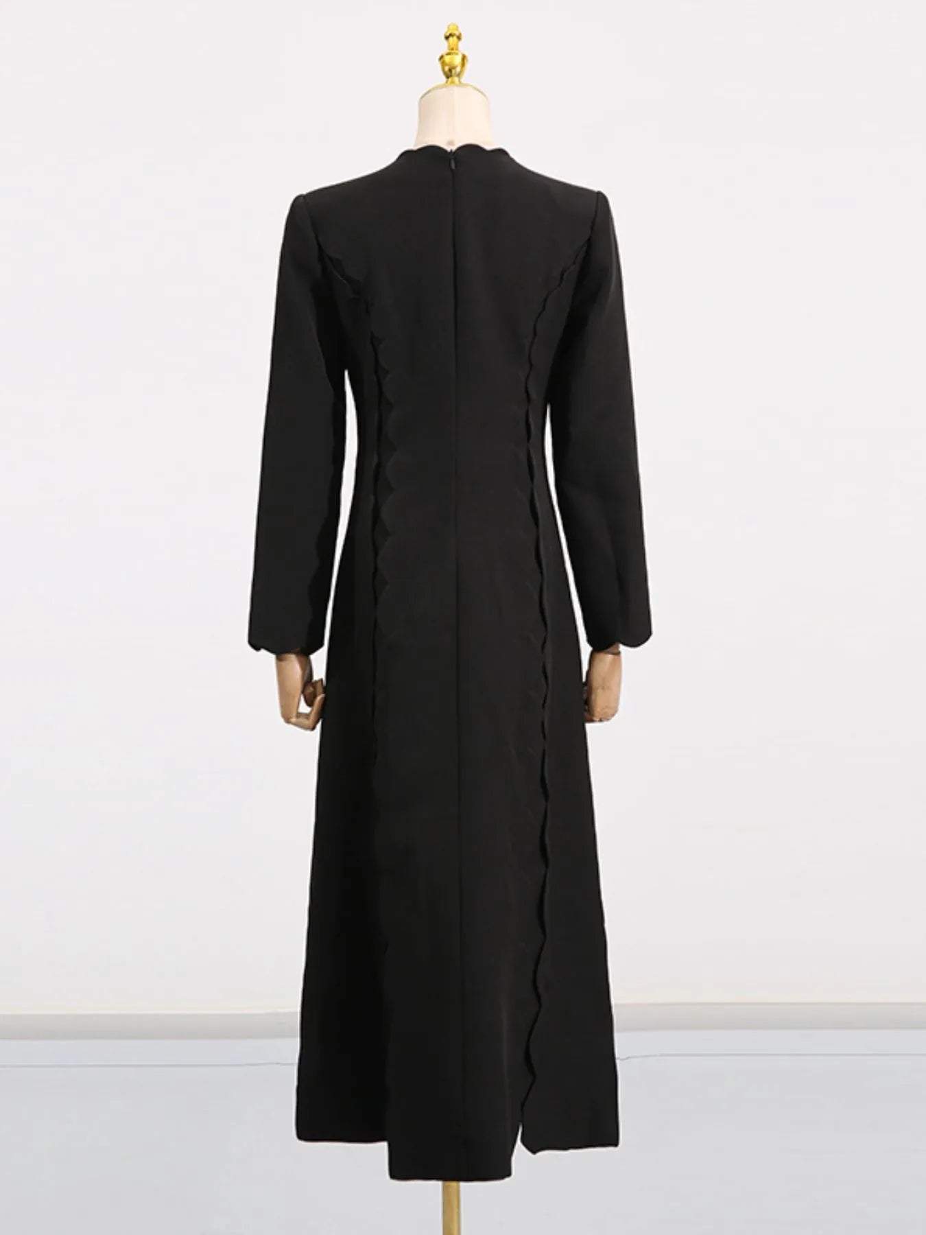 Back view of black long sleeve bow front midi dress on mannequin with fitted waist and side scallop detailing