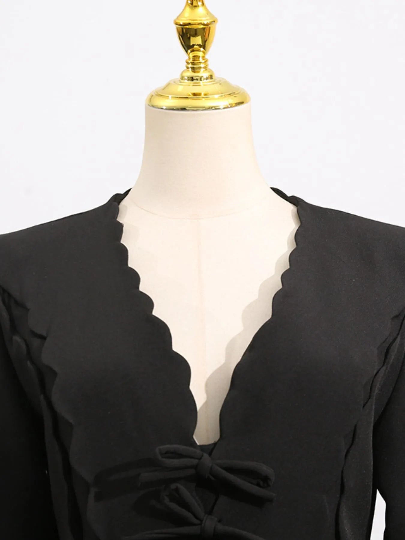 black long sleeve bow front midi dress on mannequin with scalloped V neck and front bows
