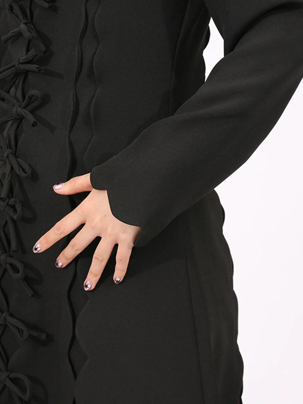 black long sleeve bow front midi dress closeup showing side bows scalloped seams and hand on hip