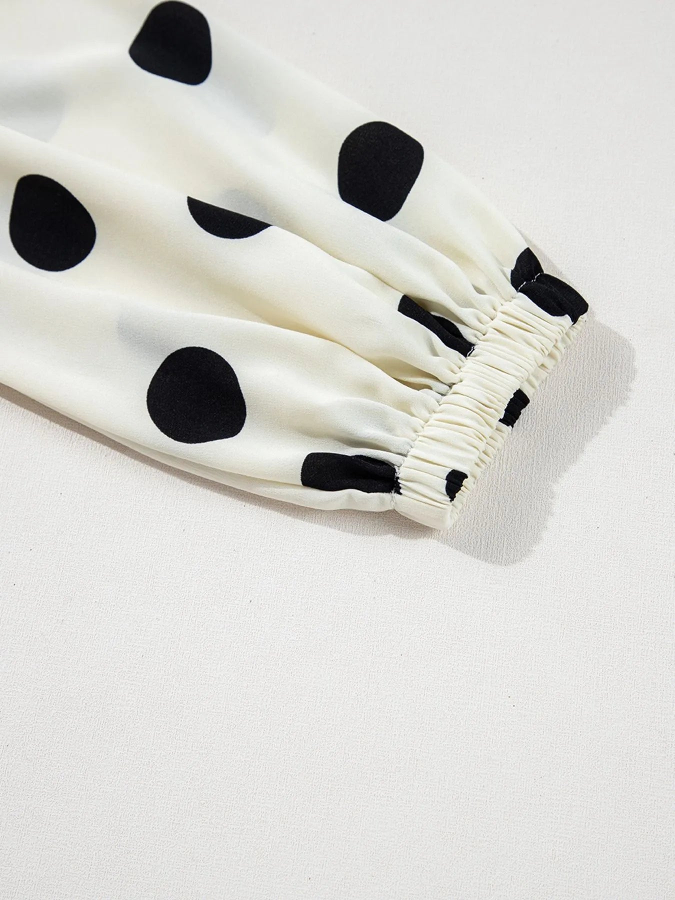 polka dot mini dress close up of white fabric with large black dots and elastic cuff puff sleeve