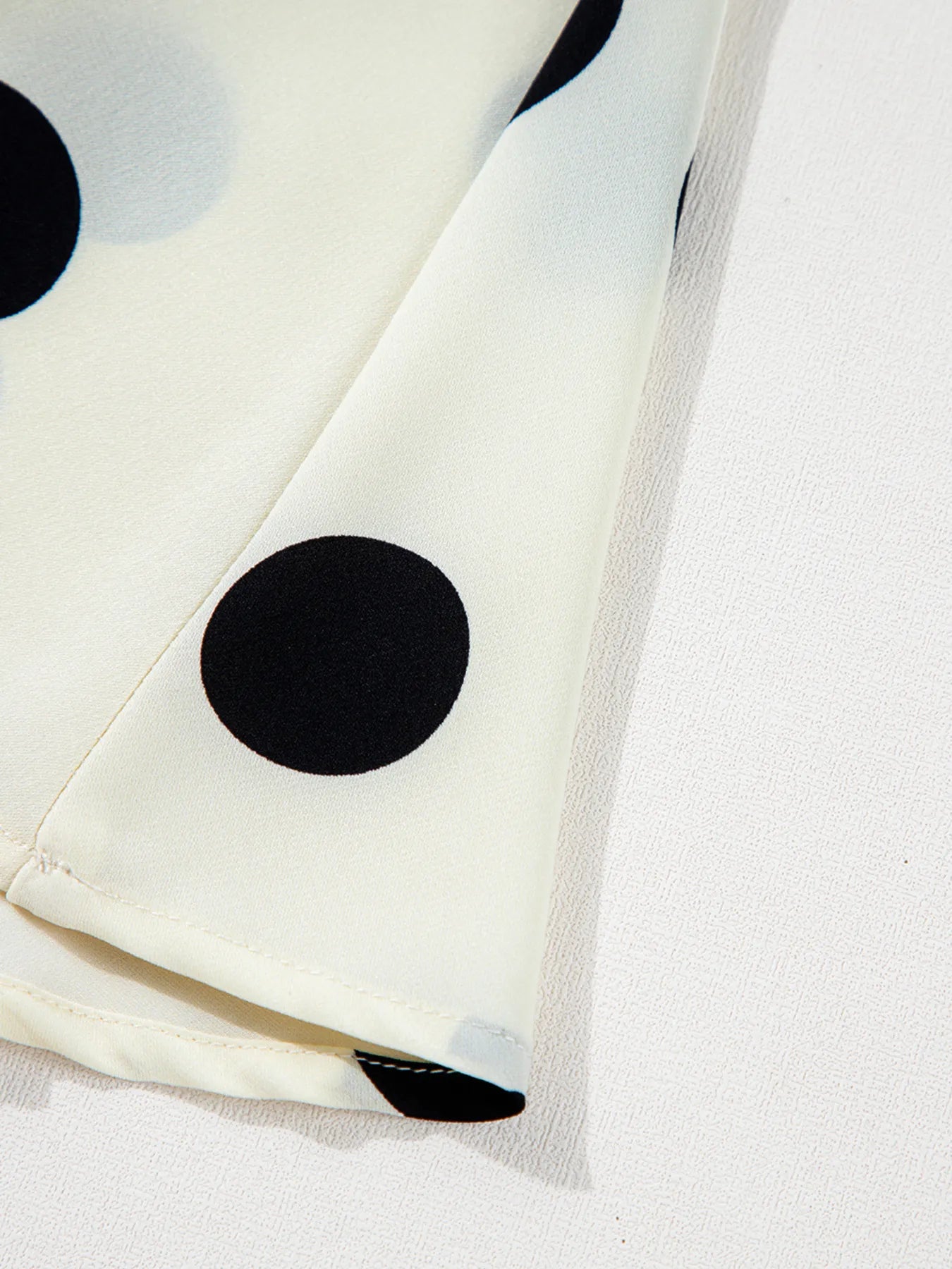 polka dot mini dress close up of ivory fabric hem with large black dots and lightweight drape