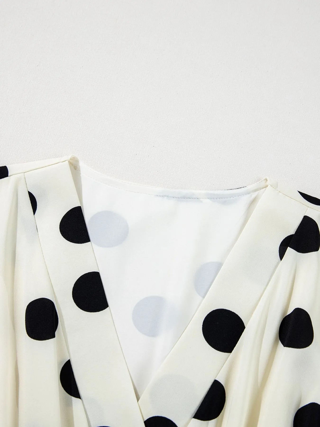 white V neck polka dot mini dress close up of bodice showing large black dots and pleated shoulders