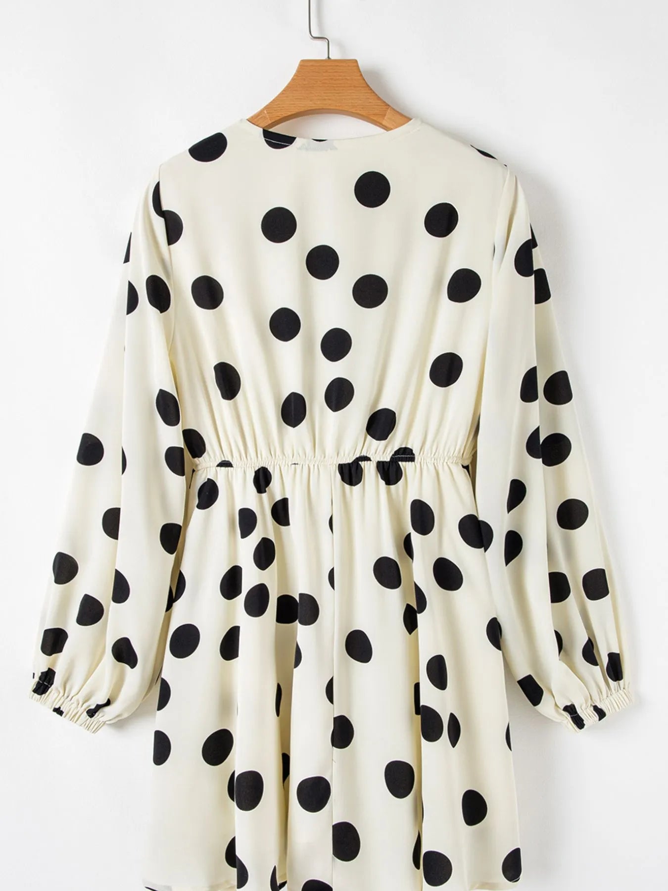 white and black polka dot mini dress with long sleeves elastic waist and ruffled hem back view