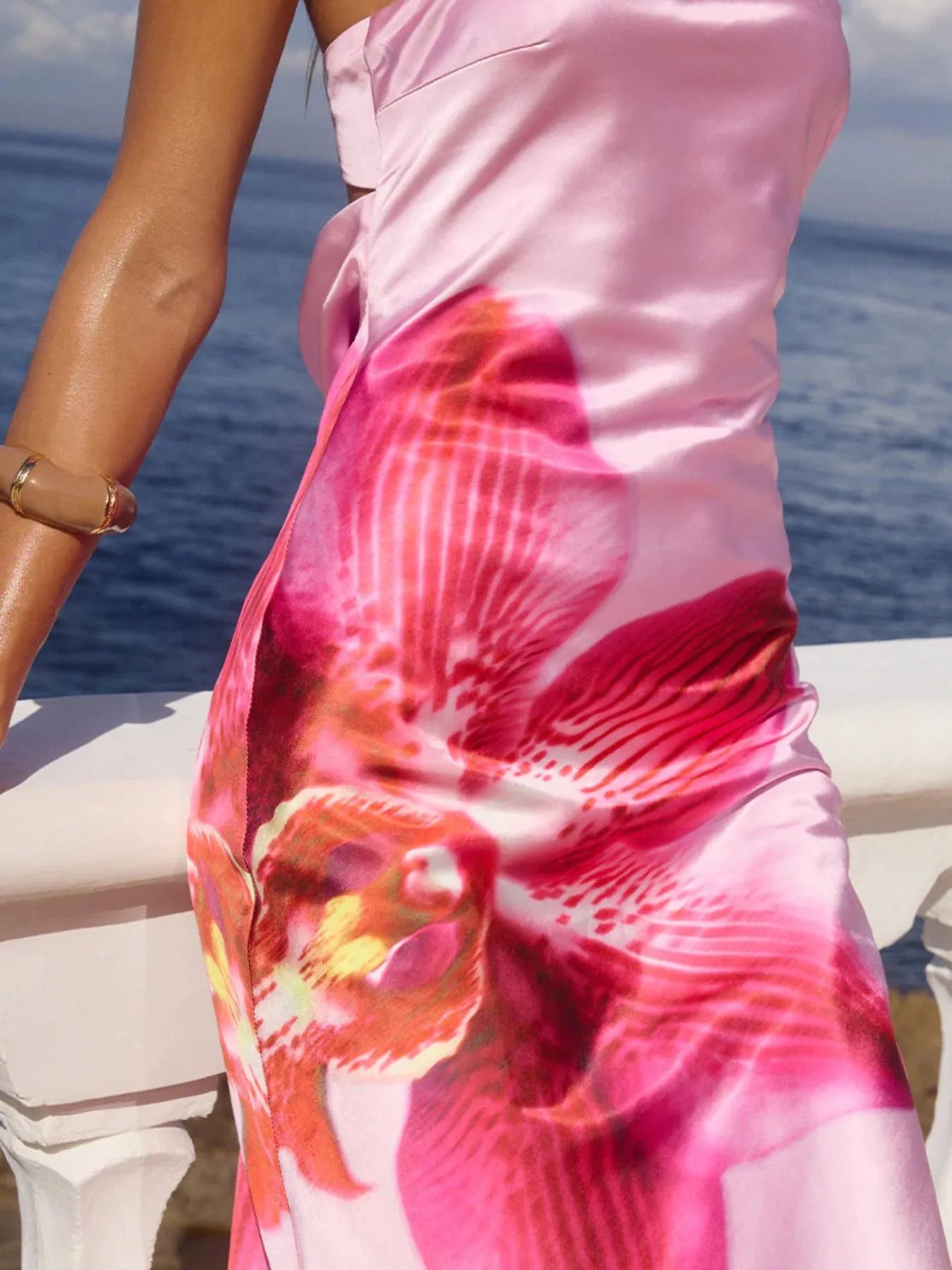 printed tube maxi dress in pink satin with large orchid print and side slit by ocean