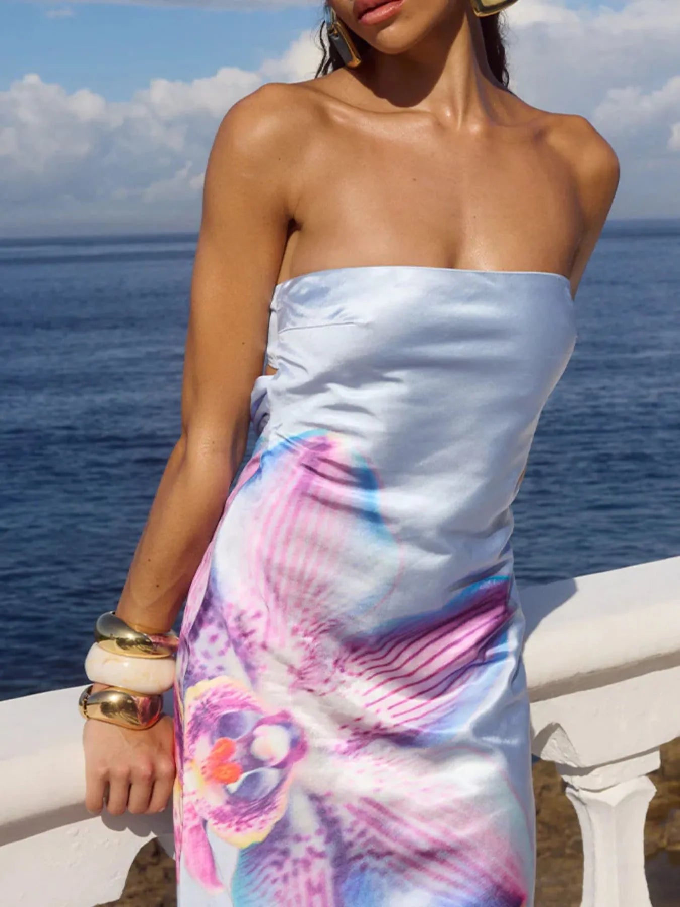 Model wearing a light blue printed tube maxi dress with large pink floral print and satin sheen