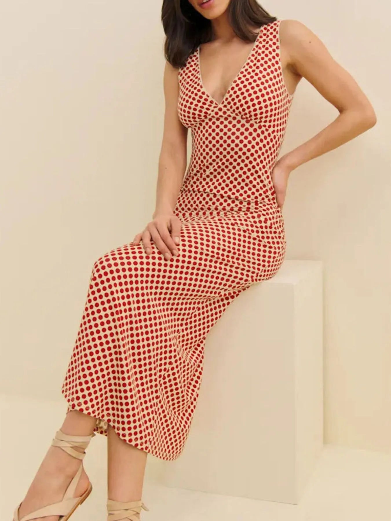 model wearing a red polka dot midi dress sleeveless V neck fitted waist and ankle length