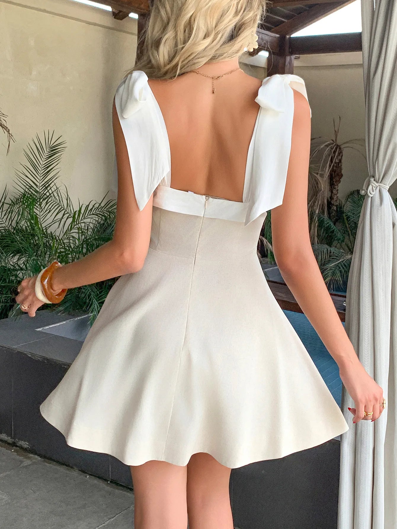 Back view of a square neck tie shoulder dress in ivory with A line skirt and back zipper closure
