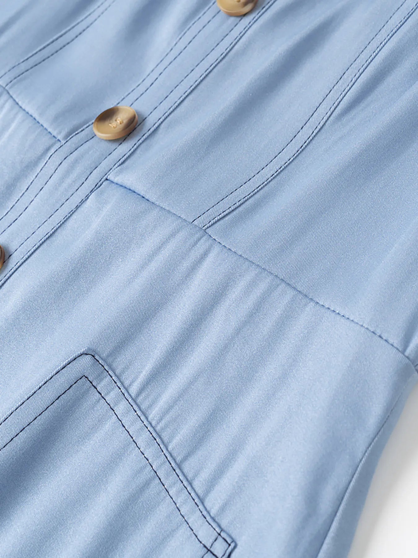 light blue wide strap denim dress closeup showing wooden buttons topstitching and front pocket