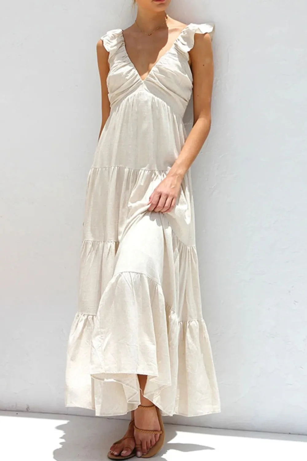 white maxi sundress featuring ruffled v-neck tiered dress silhouette with flutter sleeves and flowing tiers