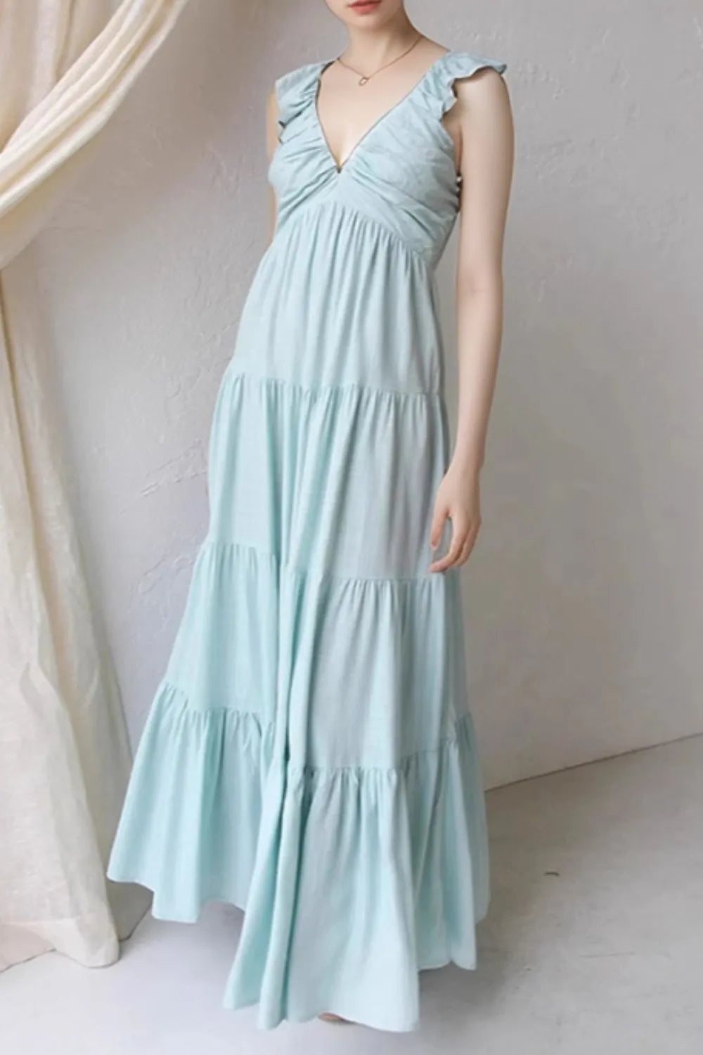light blue ruffled v-neck tiered dress with flutter sleeves and empire waist on model