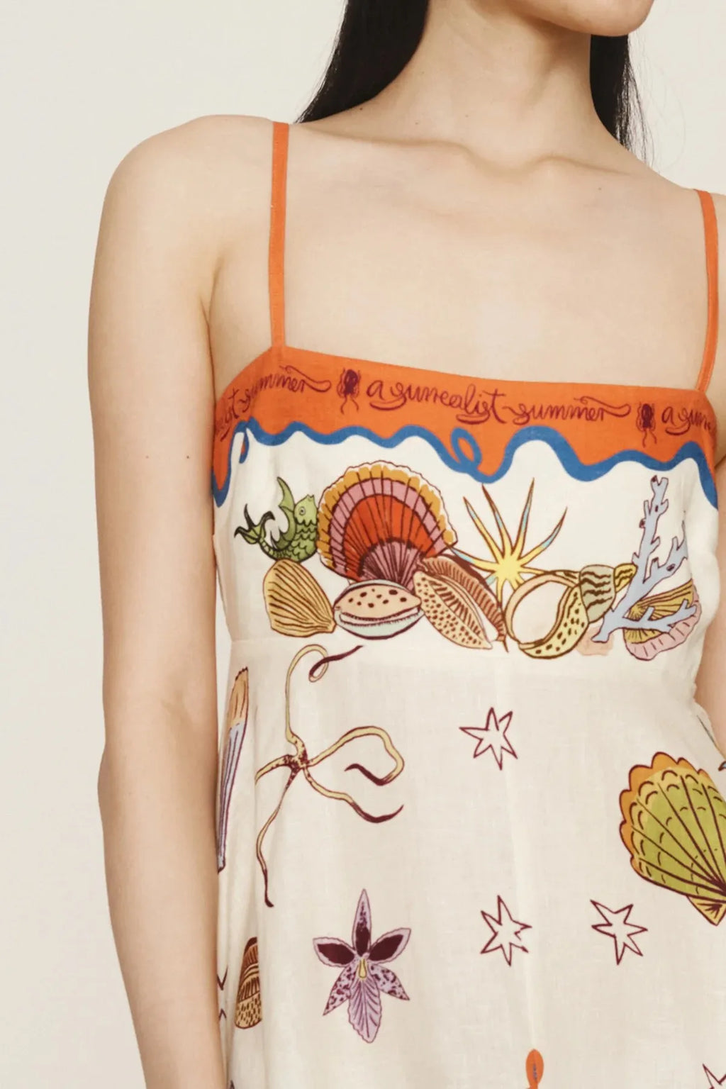 Model wearing a printed square neck maxi dress with orange trim thin straps and seashell print
