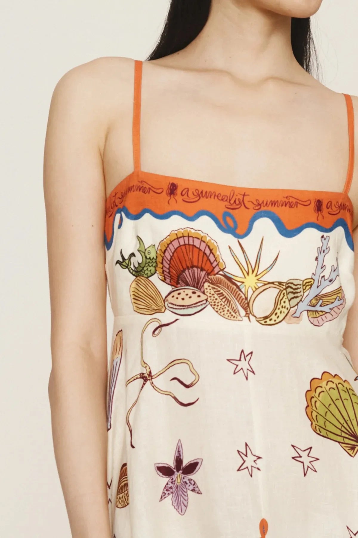 Model wearing a printed square neck maxi dress with orange trim thin straps and seashell print