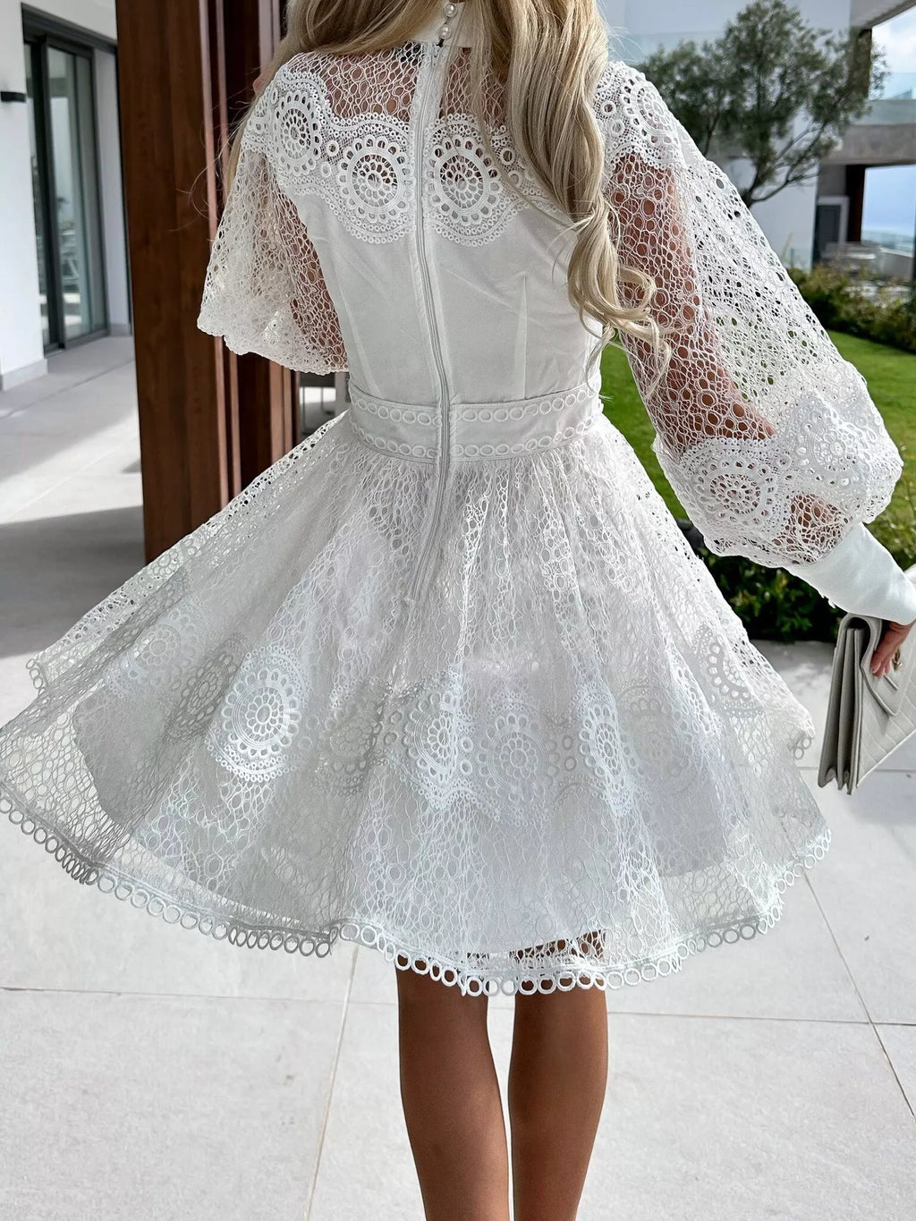 Back view of white lace lantern sleeve mini dress with fitted bodice flared skirt and intricate eyelet lace