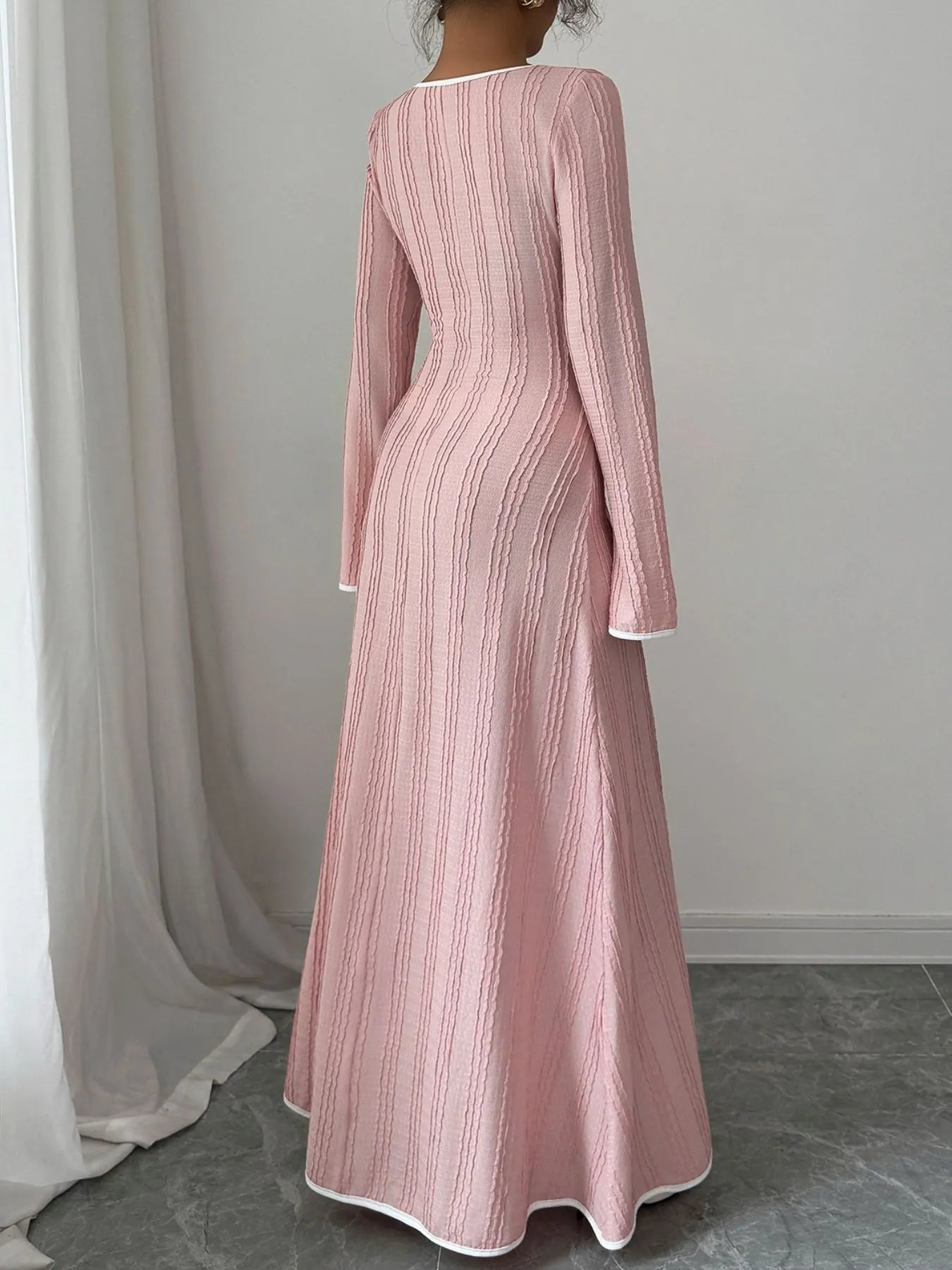 Back view of model wearing pink textured square neck maxi dress with long sleeves and subtle ribbed texture