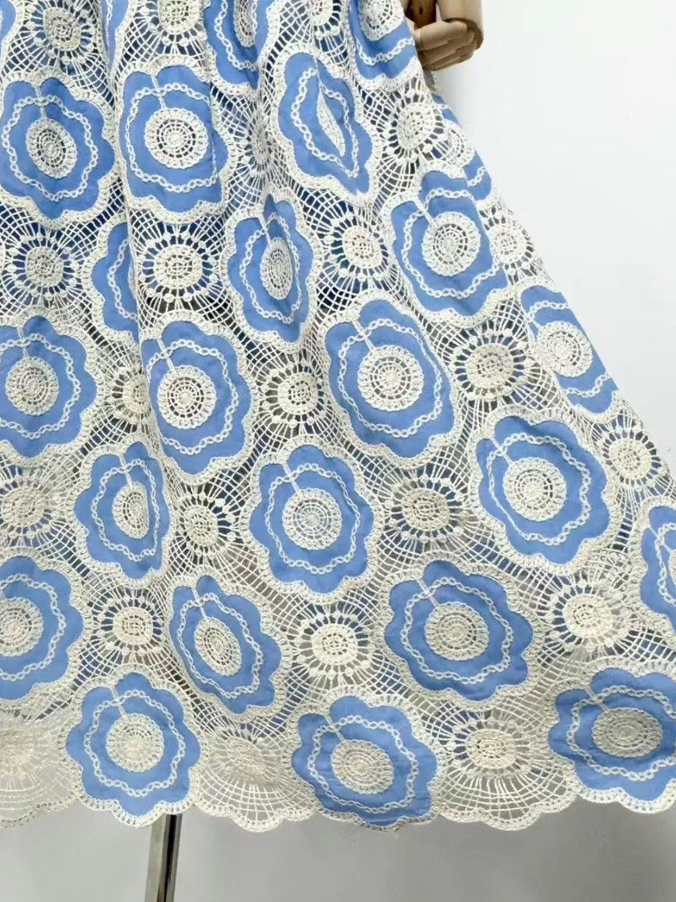 Close up of blue and white floral crochet lace panels with scalloped hem on lace tiered midi dress