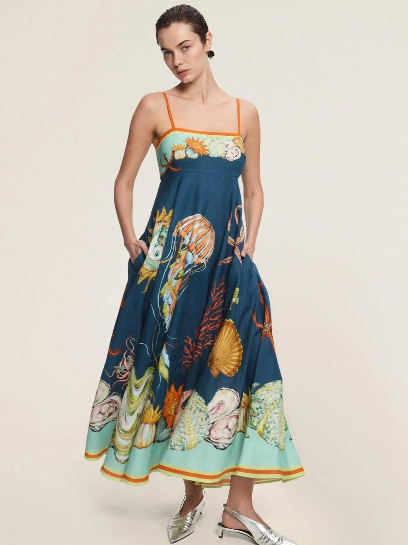 model wearing printed cami midi dress with pockets in teal seashell print orange straps and flared hem