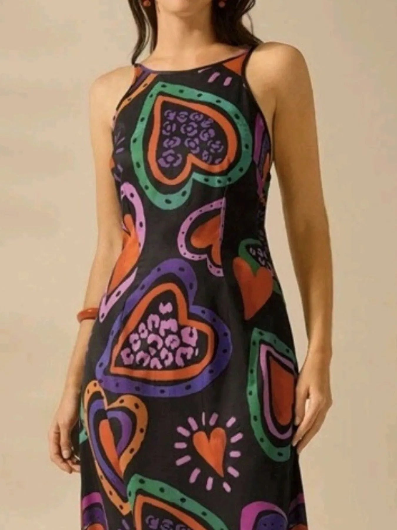 model wearing printed sleeveless maxi dress with bold multicolor heart print and high neckline