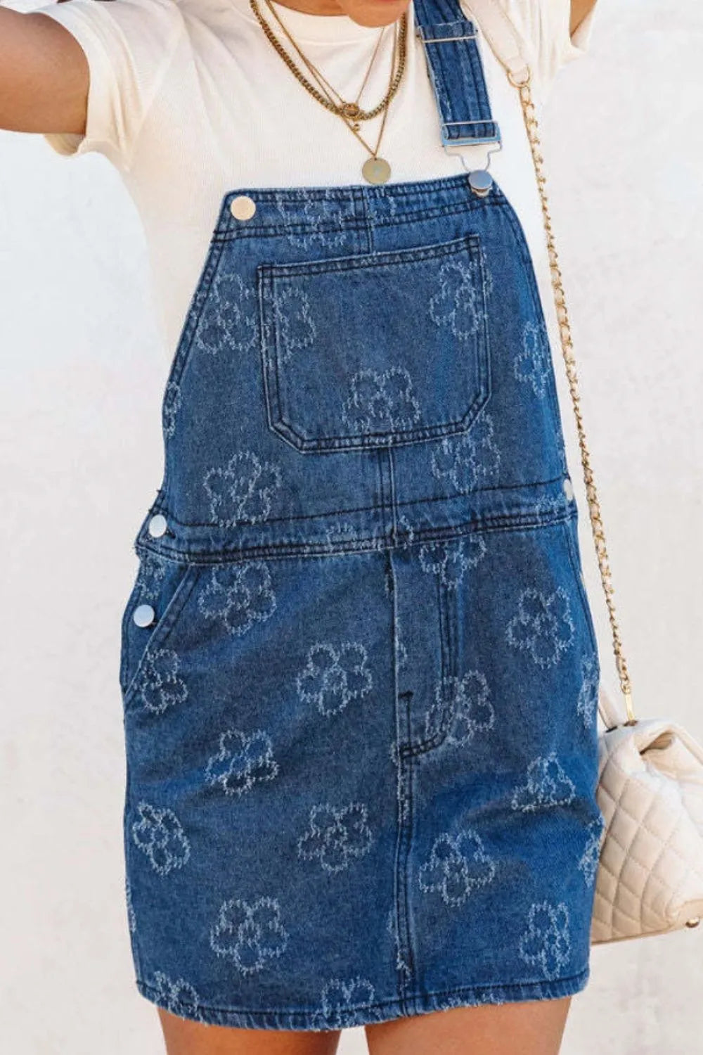 model wearing a blue flower print denim overall dress with front pocket adjustable strap